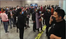  ?? (Chinatopix via AP) ?? Travelers line up to buy tickets Wednesday at a railway station in Yichang in central China’s Hubei province as trains began carrying factory employees back to work after a two-month lockdown. More photos at arkansason­line.com/326virus/.