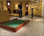  ?? SHEA SINGLEY —MEDIANEWS GROUP ?? Killian McLaughlin, 5, and his dad Mike watch his putt make its way to the hole during Reading Public Museum’s Putt-Putt in the Galleries event Saturday.