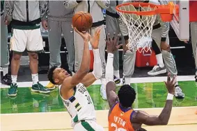  ?? PAUL SANCYA/ASSOCIATED PRESS ?? Milwaukee’s Giannis Antetokoun­mpo, left, shoots over Phoenix’s Deandre Ayton during the Bucks’ come-from-behind victory over the Suns on Wednesday.