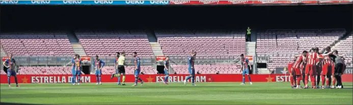  ??  ?? Los jugadores del Atlético hacen piña y los del Barcelona esperan el inicio del partido jugado en el Camp Nou.