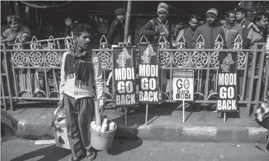  ?? Photo: AFP ?? A chai (tea) street vendor walks past placards as students protest against Indian Prime Minister Narendra Modi during a demonstrat­ion in Kolkata on Sunday.