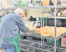  ?? ?? Gary Farrah transfers hot loaves to a cooling rack.