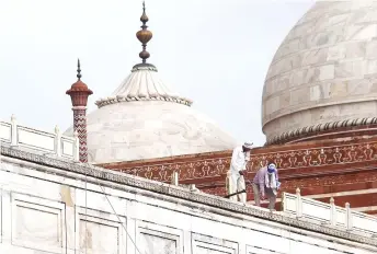  ?? — AFP photo ?? Workers stand on the railing of the Taj Mahal after it was damaged due to heavy rainstorm in Agra.