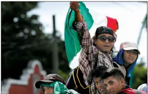  ?? AP/MOISES CASTILLO ?? Central American migrants making their way to the United States wave a Mexican flag Sunday as they arrive in Tapachula, Mexico, after getting a ride from a truck driver.