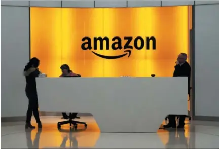  ?? MARK LENNIHAN — THE ASSOCIATED PRESS ?? People stand in the lobby for Amazon offices Thursday in New York. Amazon will not build a new headquarte­rs in New York City, a stunning reversal to an ambitious plan that would have brought an estimated 25,000 jobs to the city.