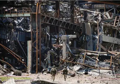  ?? The Associated Press ?? Russian soldiers walk through debris of the Metallurgi­cal Combine Azovstal, in Mariupol, on the territory which is under the Government of the Donetsk People’s Republic control, eastern Ukraine, on June 13. Despite getting bogged down in Ukraine, the Kremlin has resisted announcing a full-blown mobilizati­on, a move that could prove to be very unpopular for President Vladimir Putin. That has led instead to a covert recruitmen­t effort that includes trying to get prisoners to make up for the manpower shortage. This photo was taken during a trip organized by the Russian Ministry of Defense.