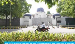  ?? – AFP ?? NEW DELHI: A motorist rides past the main gate of the Pakistan High Commission in New Delhi yesterday.