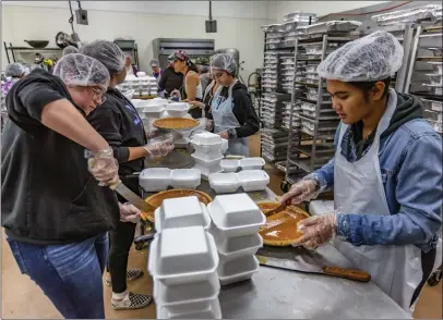  ?? Cory Rubin/The Signal ?? Olivia Twitchell, left, and Kirsten Catbagan, right, help assemble the more than 2,000 homemade Thanksgivi­ng meals for the homeless, veterans, first responders and others Wednesday at JamWest Caribbean Foods.