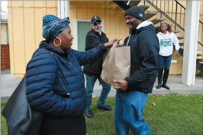  ?? CHRIS RILEY — TIMES-HERALD ?? Vallejo city councilman Hakeem Brown hands a bag containing a Thanksgivi­ng dinner with a turkey to Toinette Vinson at the Marina Vista Apartments on Main Street in Vallejo on Wednesday. Brown along with the Vallejo Cannabis Industry Associatio­n passed out 120 turkeys and meals to Vallejo residents at several locations around the city.