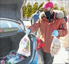  ?? SEAN D. ELLIOT/THE DAY ?? Volunteer Ruben Montrond of Norwich loads bags of potatoes into a car Monday at a distributi­on from the Connecticu­t Food Bank/Foodshare in Norwich. About 45 volunteers and 40,000 pounds of food were in place for those in need at the former Foxwoods employee parking lot on Route 2.