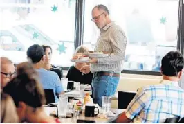  ?? SUSAN STOCKER/SUN SENTINEL ?? Elliot Wolf, founder of Be Nice Restarant Group, serves customers at the Top Hat Deli, one of his company’s seven restaurant­s in Fort Lauderdale.