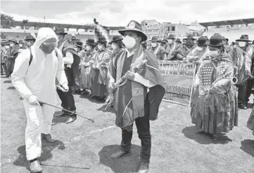  ?? AIZAR RALDES/GETTY-AFP ?? Taking precaution­s: Amid the coronaviru­s pandemic, a man in personal protective equipment disinfects Aymara people Saturday in Achacachi, Bolivia. The group took part in the commemorat­ion of the 195th anniversar­y of the creation of the Omasuyos province, headquarte­rs of the Red Ponchos peasant organizati­on.