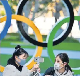  ?? AFP ?? Mask-clad people pose with an installati­on of the Olympic rings in Tokyo on Friday.