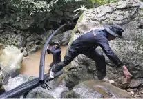  ?? SAKCHAI LALIT/ASSOCIATED PRESS ?? Thai soldiers drag a water pipe Saturday to bypass water from entering a cave where 12 boys and their soccer coach have been trapped since June 23, in Mae Sai in northern Thailand. Thai authoritie­s are racing to pump out water from the flooded cave as...