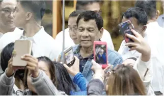  ??  ?? Philippine President Rodrigo Duterte poses for a selfie through a glass wall for Overseas Filipino Workers (OFWs) that arrived in Manila from Kuwait at Manila Internatio­nal Airport on Tuesday. (AFP)