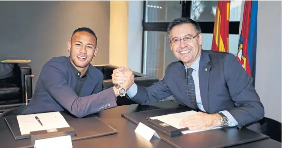  ??  ?? Neymar, left, shakes hands with Barcelona president Josep Maria Bartomeu after signing a new contract.