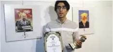  ??  ?? TEHRAN: Iranian cartoonist Hadi Asadi poses for a picture with a trophy and an award next to cartoons of US President Donald Trump at an exhibition of the Islamic Republic’s 2017 Internatio­nal Trumpism cartoon and caricature contest yesterday. —AFP