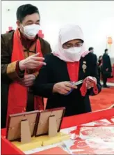  ?? DING HAITAO / XINHUA ?? Singaporea­n President Halimah Yacob tries out paper-cutting with a veteran Chinese inheritor of the non-tangible cultural heritage inside the Great Hall of the People on Feb 5.