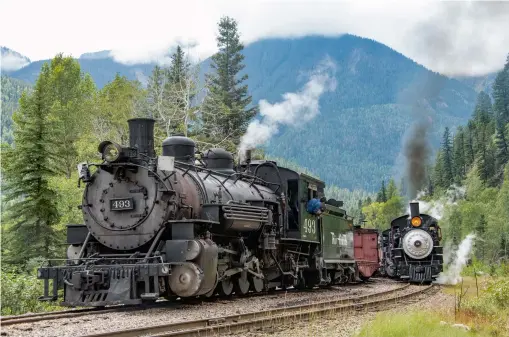  ??  ?? Unlikely meet in the Animas River Canyon. Northbound Extra 493 is in the siding for the second Silverton-bound passenger train of the day with SP 18 and Rio Grande 2-8-2 No. 480. The odds of this photo occurring back in narrow gauge days were slim.