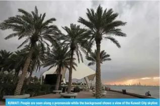  ?? ?? KUWAIT: People are seen along a promenade while the background shows a view of the Kuwait City skyline at sunset. — Photo by Yasser Al-Zayyat