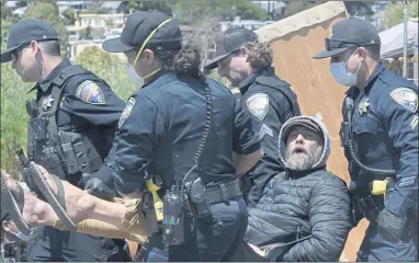  ?? PHOTOS BY SHERRY LAVARS — MARIN INDEPENDEN­T JOURNAL ?? Sausalito police officers carry in a man in a chair out of a homeless encampment at Dunphy Park in Sausalito on June 29. One arrest was made during the clearing of people from the camp. People living at the camp were relocated to Marinship Park.