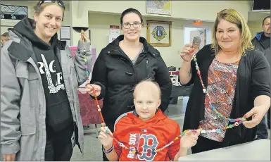  ?? "4)-&: 5)0.140/ ?? Karissa Bezanson, sitting, has some help holding out the long string of nearly 200 bravery beads that represent every medical procedure she’s undergone at the IWK Health Centre in Halifax since November. Pictured with Karissa is Jennifer Oake, Rachel...