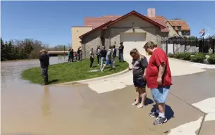  ?? EMILY ROSE BENNETT THE NEW YORK TIMES ?? People look at floodwater­s from the Tittabawas­see River in Midland, Mich., on Wednesday.