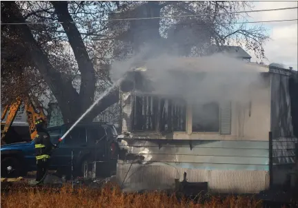  ?? JEFF RICE — JOURNAL-ADVOCATE ?? A firefighte­r pours water into the eaves of a smoldering trailer house near the former sugar factory in Sterling Tuesday.