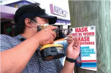  ??  ?? Restaurant workers install a signs informing guests that facemasks must be worn as Fish Tails bar and grill opens for in person dining, amid the Covid-19 pandemic in Ocean City, Maryland.