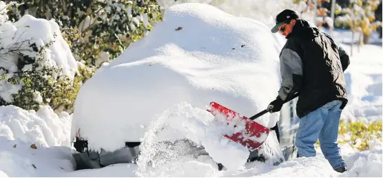  ?? DARREN MAKOWICHUK ?? Greg Schmid shovels on Wednesday to get his car out at his N.W. home following a massive October snow storm that crippled the city.