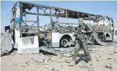  ?? — AFP ?? A rebel fighter, part of the Euphrates Shield alliance, walks past a burnt bus as they advance towards the city of Al Bab, some 30 kilometres from the Syrian city of Aleppo.