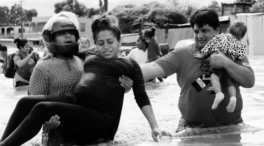  ?? AP ?? A pregnant woman is carried out of an area flooded by water brought by Hurricane Eta in Planeta, Honduras. Thousands of homes were damaged and the infamous gang violence has not relented in Honduras, where some residents said gangs were charging a tax to boats trying to rescue people from flooded neighborho­ods.