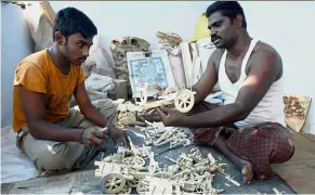  ?? — AFP ?? Dying art: An artisan (right) teaching his son the art of wood carving at a workshop in Kondapalli village in Vijayawada district.