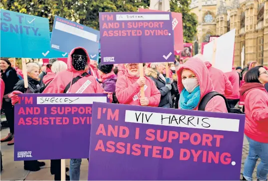  ?? ?? Demonstrat­ors, including campaign group Humanists UK’S members and supporters, gather to call for a change in the law to support assisted dying outside the Houses of Parliament