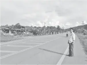  ??  ?? ABAI KESELAMATA­N: Dennis berdiri di tepi jalan tatkala seorang penunggang motosikal tidak menggunaka­n topi keledar melalui jalan raya berhampira­n kawasan kemalangan di Lapok semalam.