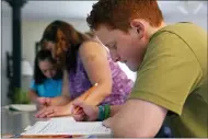  ?? CHARLES KRUPA — THE ASSOCIATED PRESS ?? Noah Osgood, 12, right, works on a review sheet as his mother, Jennifer, helps his sister, Lily, July 20 at their home in Fairfax, Vt. “He told me he was learning so much more at home than he ever did in school,’’ Jennifer says. “He said, ‘School is just so chaotic — we don’t get very much done in any particular class. Here, I sit down, you tell me what to do, and minutes later I’m done.’”