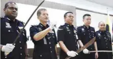  ??  ?? Gan (second from left) showing the weapons seized from the gang members.