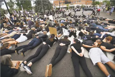  ?? Brian A. Pounds / Hearst Connecticu­t Media ?? Protesters lie face down in the middle of Boston Post Road during a Black Lives Matter protest in Fairfield Tuesday. Below, a Bridgeport police officer holds a riot shield during a protest in Bridgeport on May 30.