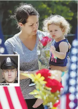  ?? STAFF PHOTOS BY ANGELA ROWLINGS ?? CHESNA PAYING TRIBUTE: Alexandra Harris and her 19-month-old daughter, Alayna, prepare to place flowers at a makeshift memorial for slain Weymouth police Sgt. Michael Chesna, while his fellow officers officers embrace outside Quincy District Court...