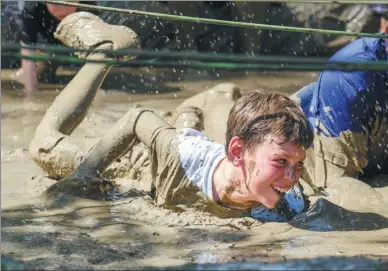  ?? ZHAO HANRONG / XINHUA ?? A competitor crawls through a mud pit at an obstacle course in Los Angeles, California, on Saturday.