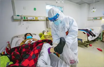  ?? CHINATOPIX VIA AP ?? A doctor checks the condition of a virus patient Thursday in Jinyintan Hospital, the site designated for critical COVID-19 patients, in Wuhan in central China’s Hubei province.