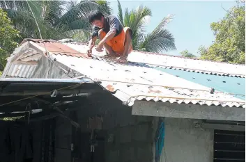 ?? PHOTOS AFP ?? Cet habitant s’affaire à sécuriser le toit de sa maison en prévision du violent typhon Mangkhut, qui doit atteindre les côtes philippine­s dès demain matin.