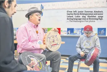  ?? — The Washington Post photos ?? (From left) junior Donovan Aimsback, teacher Kevin Kickingwom­an and senior Leland Lukin sing Blackfeet songs during language class at Browning High.