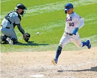  ?? KATHY WILLENS/AP ?? Marlins catcher Ryan Lavarnway, left, has no play at the plate as the Mets’ Andres Gimenez scores on a sacrifice fly to center field during the sixth inning of Sunday’s game.