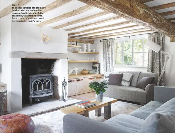  ??  ?? SNUG
The bespoke fitted oak cabinetry, finished with leather handles, was designed to blend with the beautifull­y weathered beams. Tetrad Lewis sofa in Harris tweed, £1,500, John Lewis & Partners