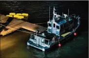  ?? ANDRES KUDACKI / AP ?? Yellow buoys that a New York police officer said are suspending a helicopter that crashed into the East River float next to an NYPD police boat at a pier in New York on Sunday. The helicopter crashed into New York City’s East River Sunday night,...