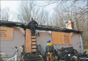  ?? Leslie Hutchison / Hearst Connecticu­t Media ?? Workers on Jan. 4 place plywood over the windows to secure the house after a fatal three-alarm fire a day earlier.