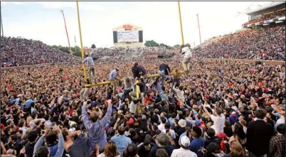  ?? AP/The Daily Mississipp­ian/THOMAS GRANING ?? Thousands of Ole Miss students and supporters storm the field and attempt to bring down the goal posts Saturday after the No. 11 Rebels stunned No. 3 Alabama at Vaught-Hemingway Stadium in Oxford, Miss.