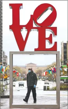  ??  ?? A person wearing a protective face mask walks by the Robert Indiana sculpture LOVE on Monday at John F. Kennedy Plaza, commonly known as Love Park, in Philadelph­ia.
(AP/Matt Rourke)
