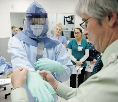  ?? CHARLES REX ARBOGAST/THE ASSOCIATED PRESS ?? Nurse Keene Roadman, left, and Fred Serafin demonstrat­e proper protective procedures Thursday to doctors and nurses, who may be called upon to treat Ebola patients, during a training class at the Rush University Medical Center in Chicago.